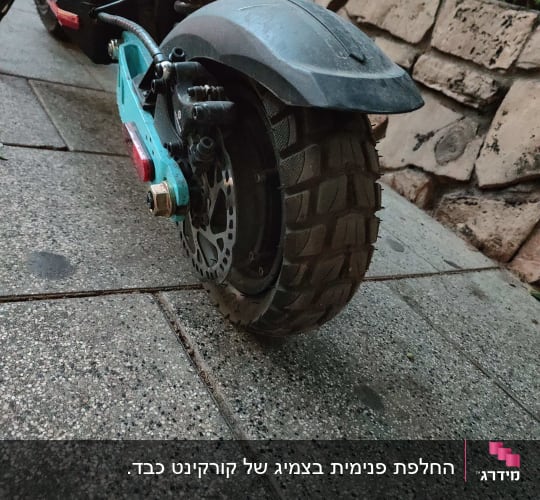 גלגל אחורי של קורקינט עם בלם דיסק על מדרכה
